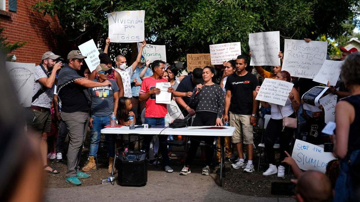 Resident Jaun Carlos Jimenez, center left, listens as Jeraldine Mazo, center right, speaks during a rally staged by the East Colfax Community Collective to address chronic problems in the apartment buildings occupied by people displaced from their home countries in central and South America Tuesday, Sept. 3, 2024, in Aurora, Colo. David Zalubowski/AP