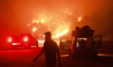 A resident walks by his car packed with belongings as Highway 330 is engulfed by the Line Fire near Running Springs