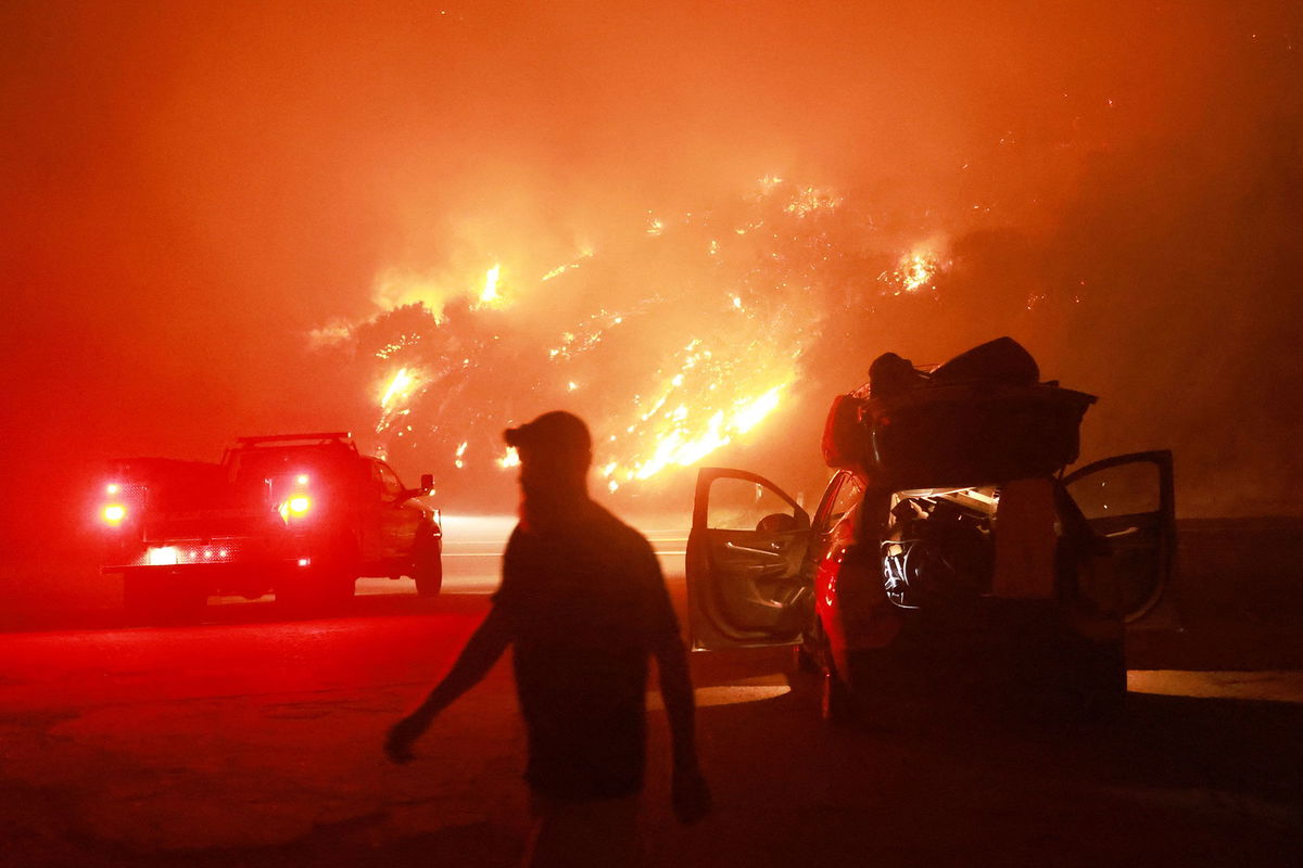 <i>David Swanson/AFP/Getty Images via CNN Newsource</i><br/>A resident walks by his car packed with belongings as Highway 330 is engulfed by the Line Fire near Running Springs