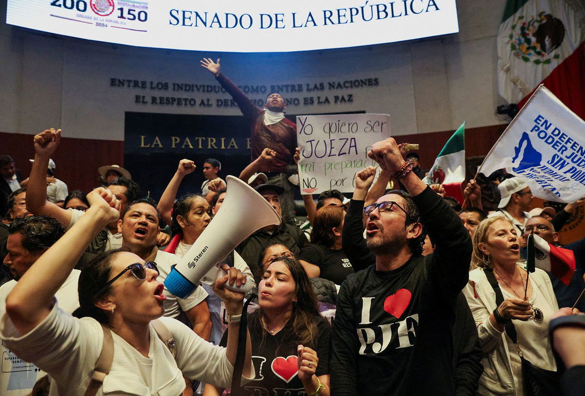 <i>Luis Cortes/Reuters via CNN Newsource</i><br/>Demonstrators wave Mexican flags after entering the Senate building in Mexico City on September 10.