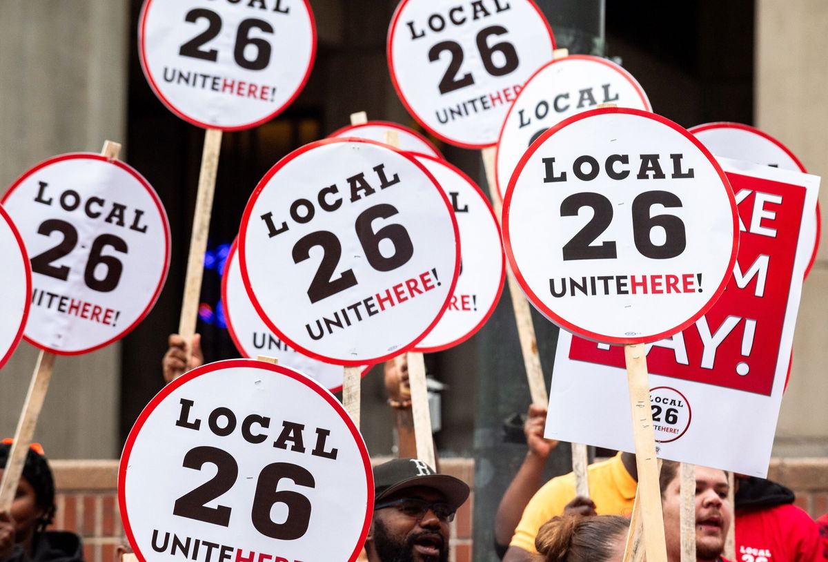 People hold UNITE HERE Local 26 signs at a press conference after a strike authorization vote by UNITE HERE Local 26 on August 8.