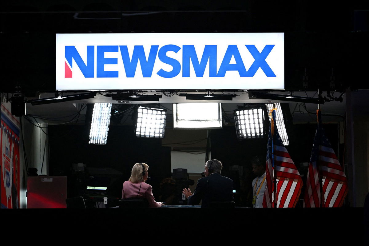 <i>Patrick T. Fallon/AFP/Getty Images via CNN Newsource</i><br/>News anchors work at Newsmax's booth during the second day of the 2024 Republican National Convention at the Fiserv Forum in Milwaukee