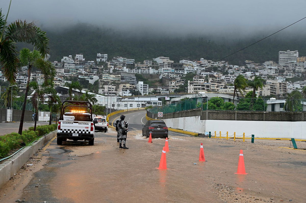 <i>Francisco Robles/AFP/Getty Images via CNN Newsource</i><br/>Security forces stands guard on a flooded road after Hurricane John in Acapulco