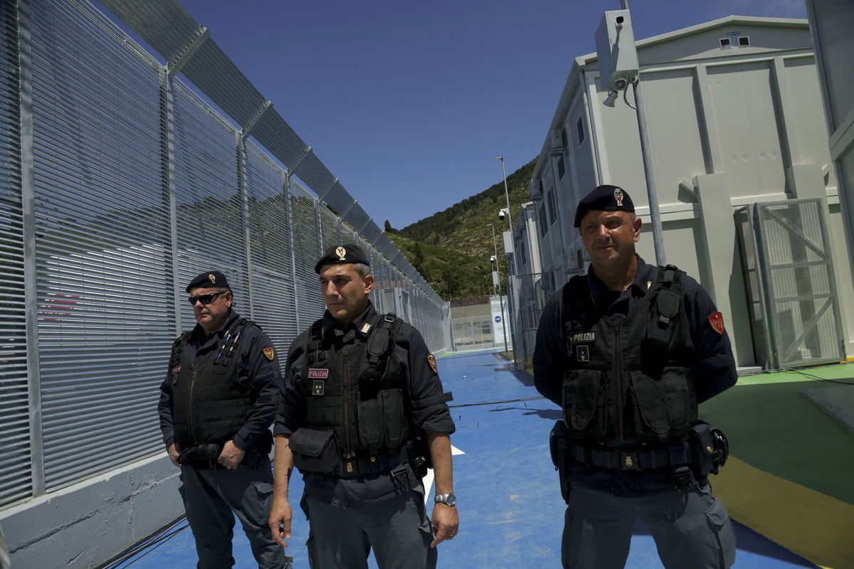 <i>Adnan Beci/AFP/Getty Images via CNN Newsource</i><br/>An Albanian walks in front of the main gate talking on a radio at an Italian-run migrant center located within an old military camp in Gjader