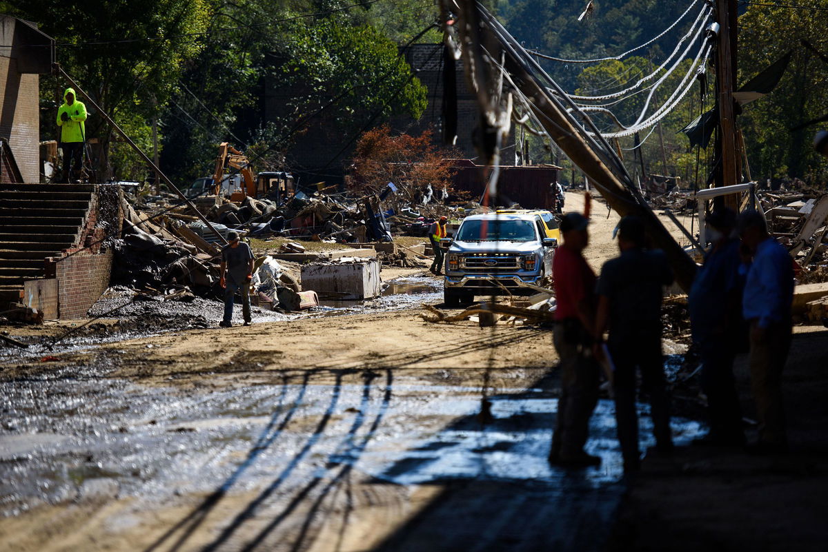 <i>Tom Brenner/Reuters via CNN Newsource</i><br/>First responders watch President Joe Biden's motorcade against the backdrop of damaged properties in Keaton Beach