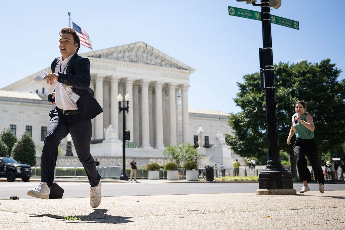 <i>Drew Angerer/AFP/Getty Images via CNN Newsource</i><br/>A journalist runs across the US Supreme Court plaza carrying an opinion to a news correspondent as the court handed down decisions on July 1 in Washington