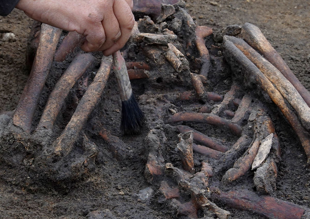 <i>Tom Little/Reuters via CNN Newsource</i><br/>Archaeologists excavate skeletons in a pit at the Viking-age burial site in the village of Asum