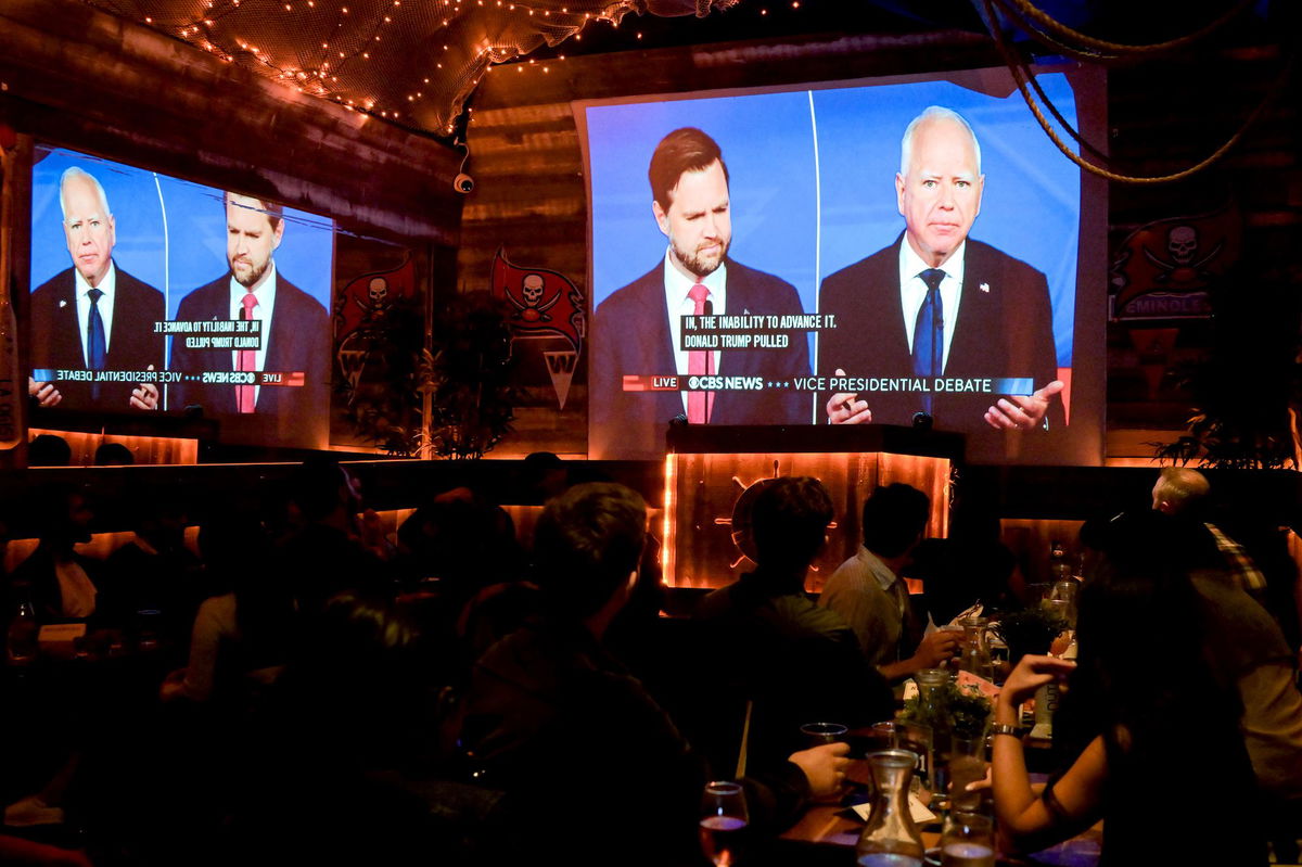 <i>Victor J. Blue/Bloomberg/Getty Images via CNN Newsource</i><br/>Sen. JD Vance and Gov. Tim Walz are shown on screen during a vice presidential debate watch party in New York on October 1.