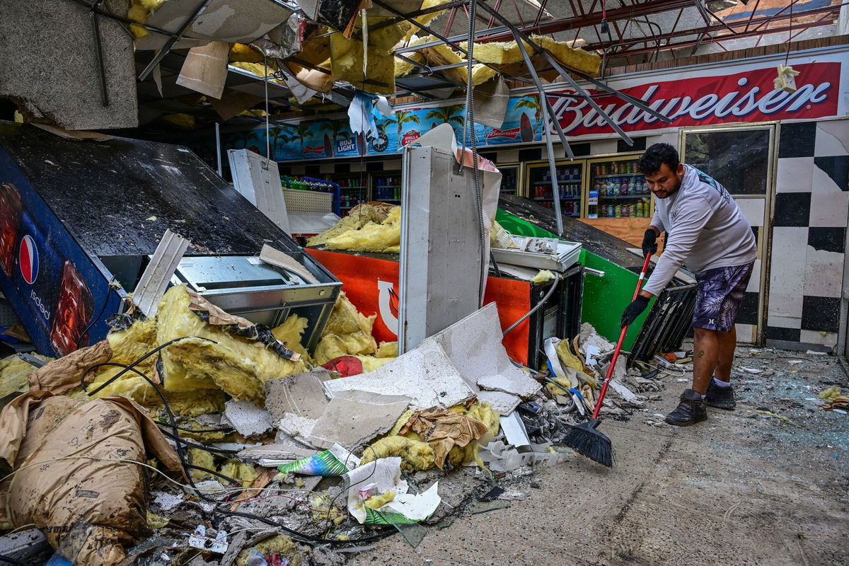 <i>Giorgio Viera/AFP/Getty Images via CNN Newsource</i><br />A man cleans debris inside a gas station store in Lakewood Park