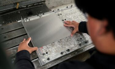 A worker places metal in a milling machine while producing parts for a Boeing 777 jetliner at Pathfinder Manufacturing