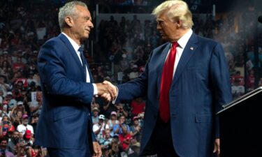 Robert F. Kennedy Jr. and former President Donald Trump shake hands during a campaign rally at Desert Diamond Arena on August 23