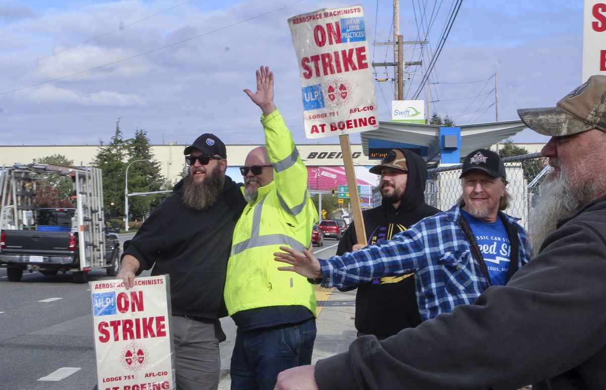 <i>Manuel Valdes/AP via CNN Newsource</i><br/>Union machinists wave signs next to the company's factory in Everett