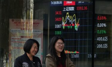 Women walk past a display showing the Shanghai stock market index outside a brokerage in Beijing on Wednesday