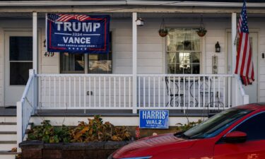 A Trump/Vance campaign flag hangs in front of one side of a duplex home while a Harris/Walz campaign sign is seen in front of the other side in Pen Argyl