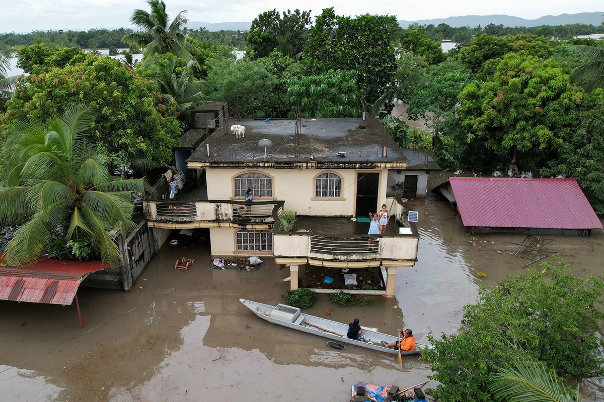 <i>Charism Sayat/AFP/Getty Images via CNN Newsource</i><br/>Residents cross a bridge filled with debris due to heavy rains brought about by Tropical Storm Trami in Polangui town