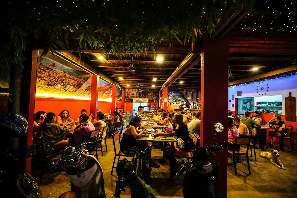 <i>Anupam Nath/AP via CNN Newsource</i><br/>Tourists eat dinner at a hostel in Vang Vieng