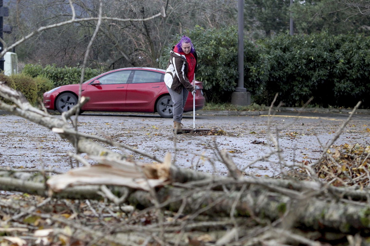 <i>Manuel Valdes/AP via CNN Newsource</i><br/>Erica Leinbach cleans up debris from fallen trees after a bomb cyclone storm brought high winds to Issaquah