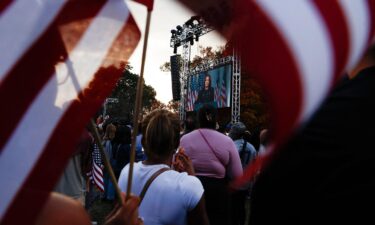 Supporters of Democratic presidential nominee Vice President Kamala Harris listen as she is seen in a screen delivering remarks