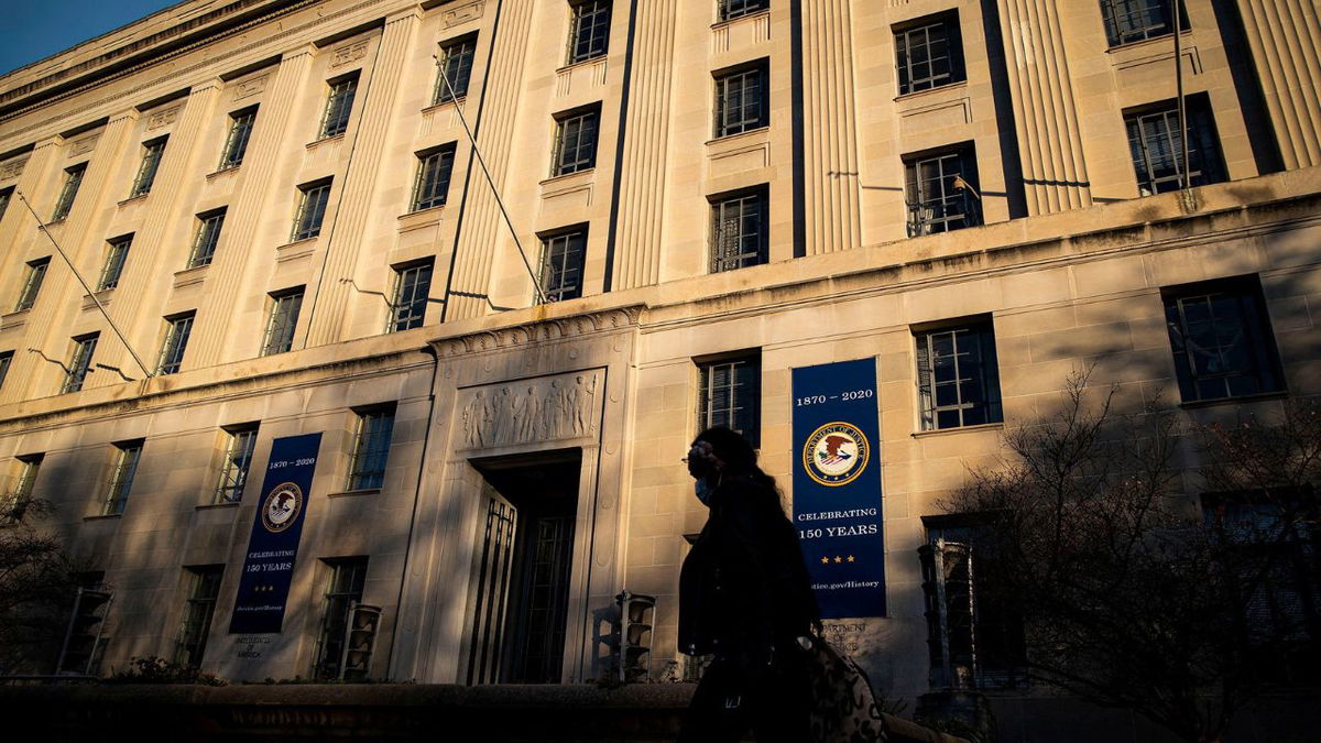 In this 2020 photo, a woman walks past the US Department of Justice in Washington, DC.
