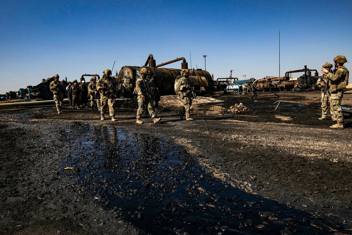 <i>Delil Souleiman/AFP/Getty Images via CNN Newsource</i><br/>US soldiers inspect the site of reported Turkish shelling days earlier on an oil extraction facility on the outskirts of Rumaylan