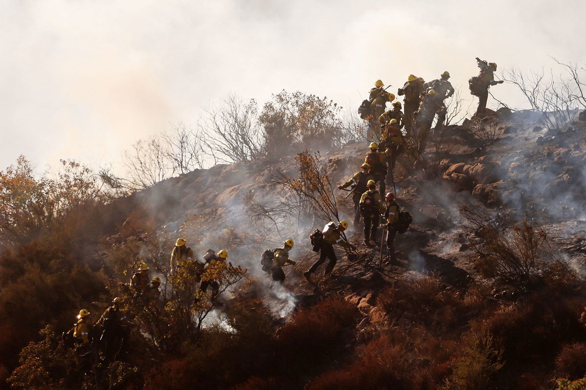 <i>Mario Tama/Getty Images via CNN Newsource</i><br/>Firefighters work as the Franklin Fire burns near a building on Tuesday in Malibu