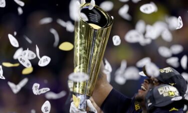 A player with the Michigan Wolverines raises the College Football Playoff National Championship Trophy after the Wolverines defeated the Washington Huskies in January.