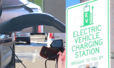 A electric car gets charged next to a sign reading "Electric Vehicle Charging Station."