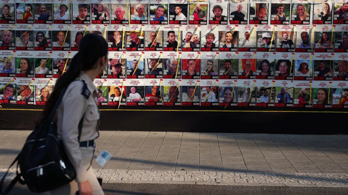 <i>Florion Goga/Reuters via CNN Newsource</i><br />A woman passes posters of hostages kidnapped during the deadly October 7 attack on Israel by Hamas