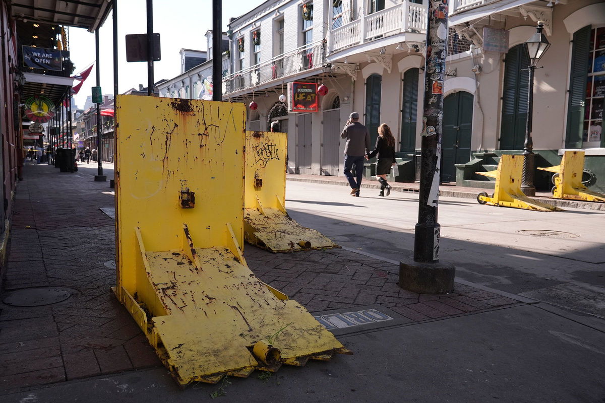 <i>George Walker IV/AP via CNN Newsource</i><br/>Tourists walk past temporary barriers on Bourbon Street in New Orleans