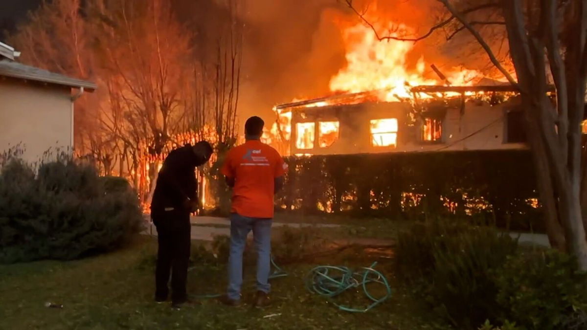 <i>CNN via CNN Newsource</i><br/>Volunteers try to douse Gail's home and yard to keep the flames at bay.