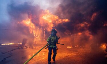 A firefighter battles the Palisades Fire as it burns during a windstorm on the west side of Los Angeles