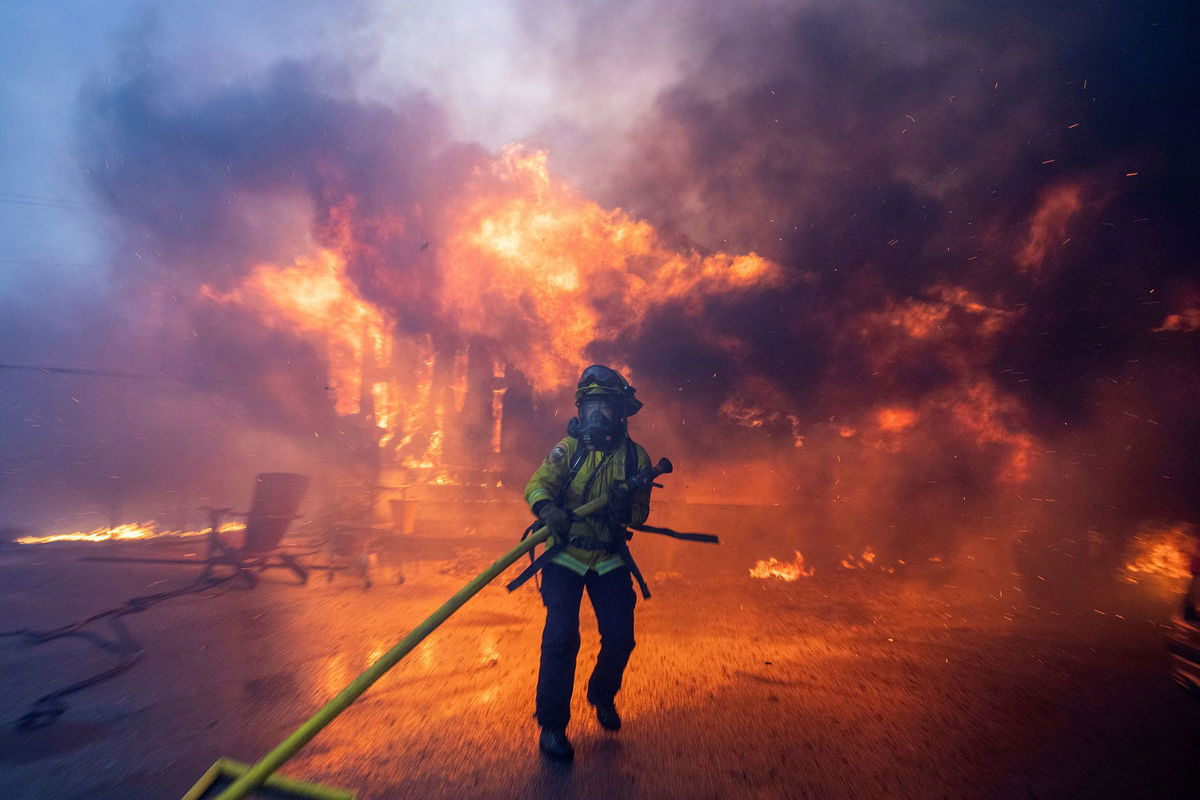 <i>Ringo Chiu/Reuters via CNN Newsource</i><br/>A firefighter battles the Palisades Fire as it burns during a windstorm on the west side of Los Angeles