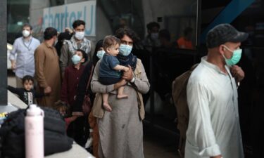 Refugees board a bus at Dulles International Airport that will take them to a refugee processing center after being evacuated from Kabul following the Taliban takeover of Afghanistan on August 31