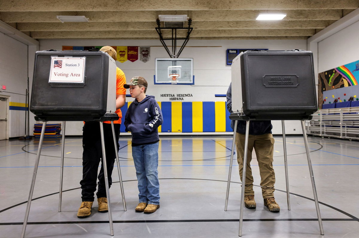<i>Jonathan Drake/Reuters via CNN Newsource</i><br/>A boy watches his father voting for the 2024 U.S. presidential election
