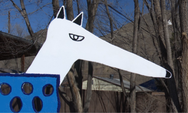 A close up of the sculpture, which shows a dog with a white head and a blue, boxy body.