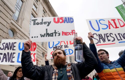 Protesters hold signs during a press conference held by several members of congress in front of the headquarters for United States Agency for International Development (USAID) on February 3 in Washington