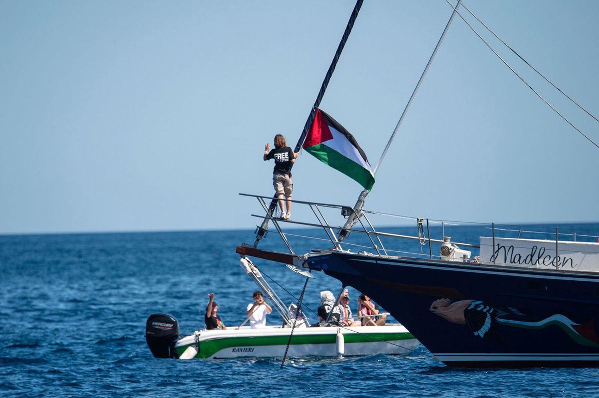 <i>Salvatore Cavalli/AP via CNN Newsource</i><br/>Climate activist Greta Thunberg stands next to a Palestinian flag after boarding the Madleen and before setting sail for Gaza with the Freedom Flotilla Coalition
