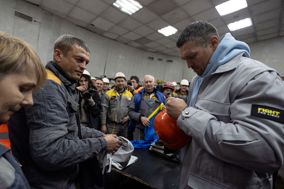 <i>Valentyn Ogirenko/Reuters via CNN Newsource</i><br/>Oleksandr Usyk signs a protective helmet in March as he visits a thermal power plant in Ukraine that had been damaged by Russian missile strikes.