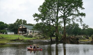 A search and rescue team looks for people along the Guadalupe River near a damaged building at Camp Mystic in Texas