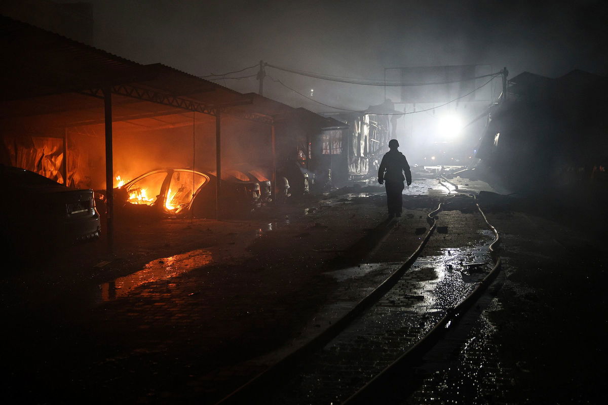 <i>Kateryna Klochko/AP via CNN Newsource</i><br/>A rescue worker walks on a parking of car repair service destroyed by a Russian drone strike in Zaporizhzhia
